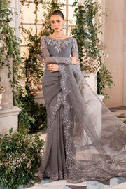 A woman in a traditional Maria B, unstitched gray wedding suit with embroidered details and a saree fall