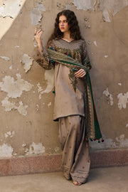 Woman in traditional outfit standing against a textured wall