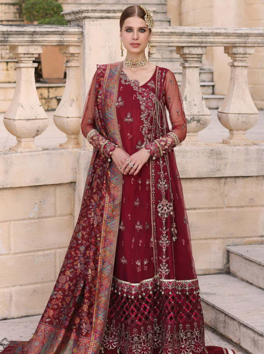 A woman wearing a traditional, embroidered, maroon-colored 3-piece suit with sequins and tilla embroidery, including detailed leaf patterns, and a net stole.