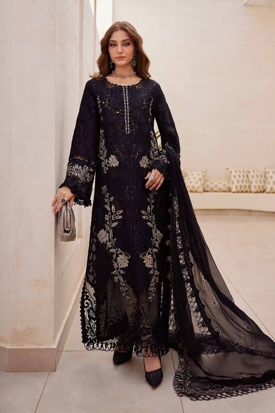 A woman wearing a black three-piece embroidered suit with organza details, from the Maria.B Unstitched Luxury Lawn Eid Collection.