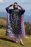 Woman in a traditional outfit with floral patterns standing in a scenic outdoor setting with mountains and greenery.