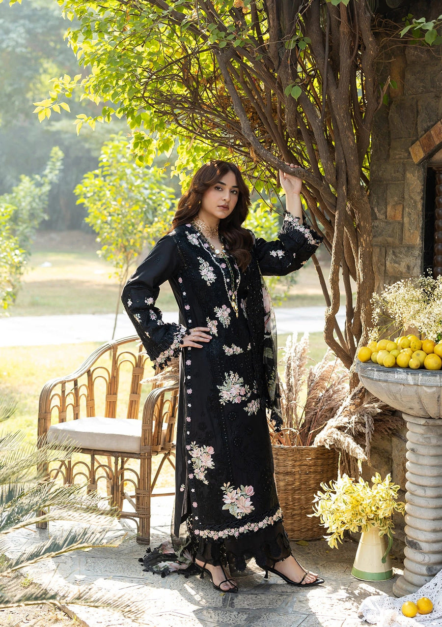 Woman in a black floral dress standing outdoors near a tree and bench.