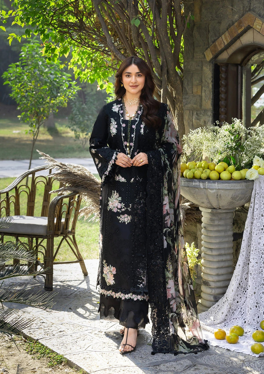Woman in a black floral dress standing outdoors with greenery and fruit in the background