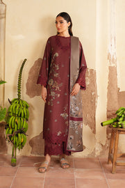Woman in a burgundy floral dress standing in a room with plants and a textured wall.