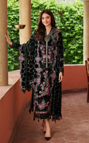 Woman in a black floral dress standing outdoors with greenery in the background