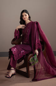 Woman in a purple traditional outfit sitting on a chair against a plain background