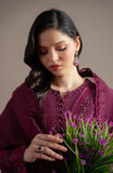 Woman in a purple traditional outfit holding a bouquet of purple flowers against a neutral background