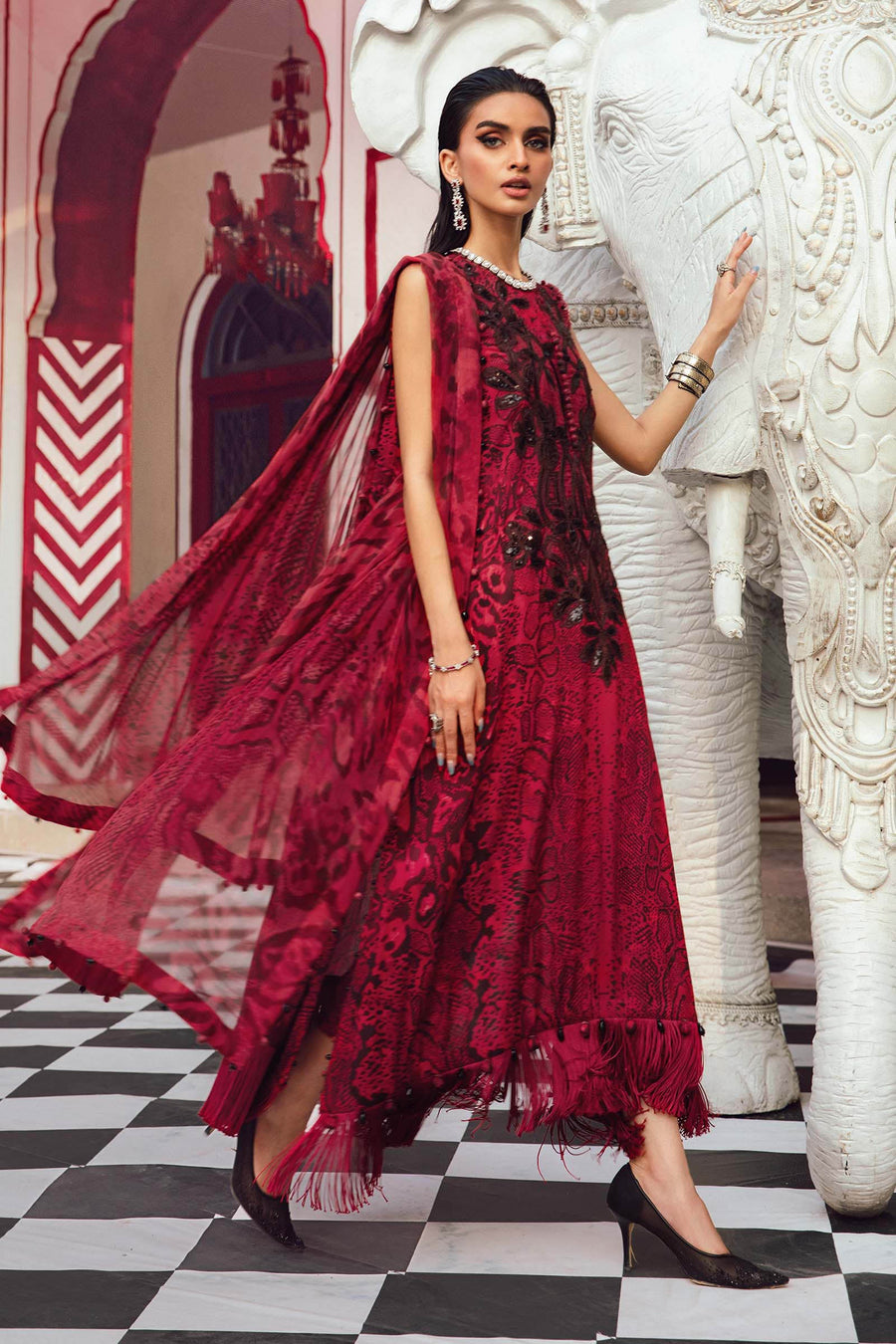 Woman in a red dress standing next to an elephant in a decorated setting