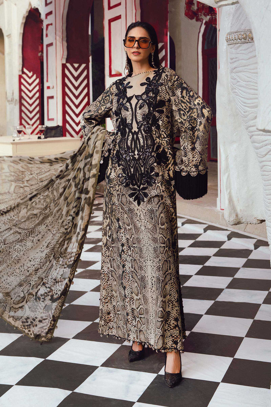Woman in a patterned dress standing on a checkered floor with decorative walls.