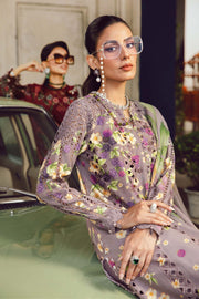 Woman in a floral dress sitting on a car, with another person in the background.