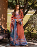 Woman in a traditional outfit with a patterned shawl standing outdoors near a tree.