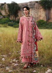 Woman in a pink embroidered traditional outfit standing in a natural setting.