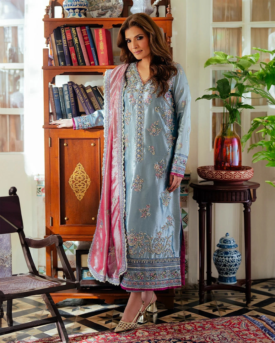 Resham  in a light blue embroidered outfit with pink dupatta standing in a decorated room. Mush Suehri Ramsha Eidt