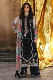 Woman wearing a black embroidered outfit with a colorful scarf against a gold curtain background
