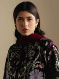 Woman wearing a dark floral embroidered garment with a plain background